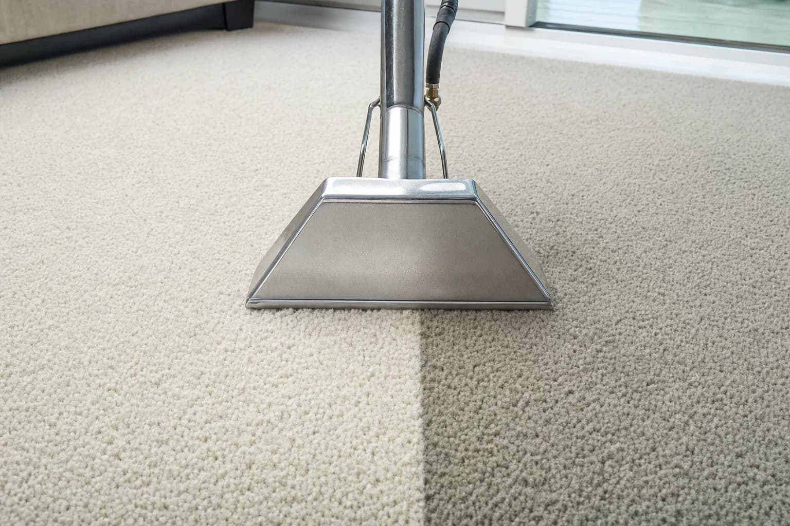 A carpet cleaning wand head part way through a pass, cleaned pile beside untouched pile
