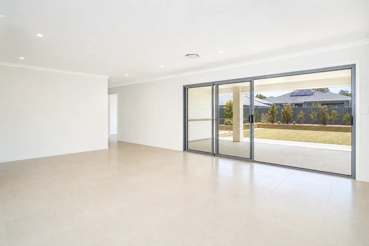 An empty tiled open plan living area in a Perth rental, sliding stacker doors open to a paved alfresco