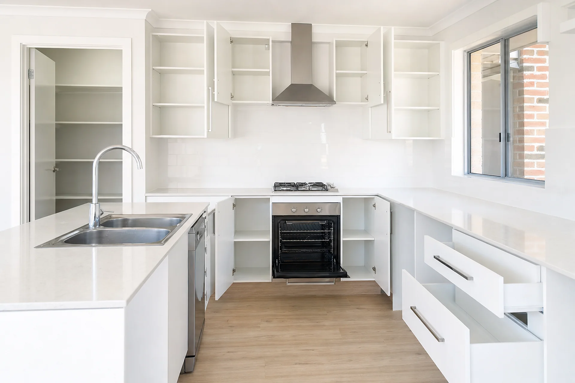 A deep cleaned kitchen with the oven and cupboard doors open showing cleaned interiors