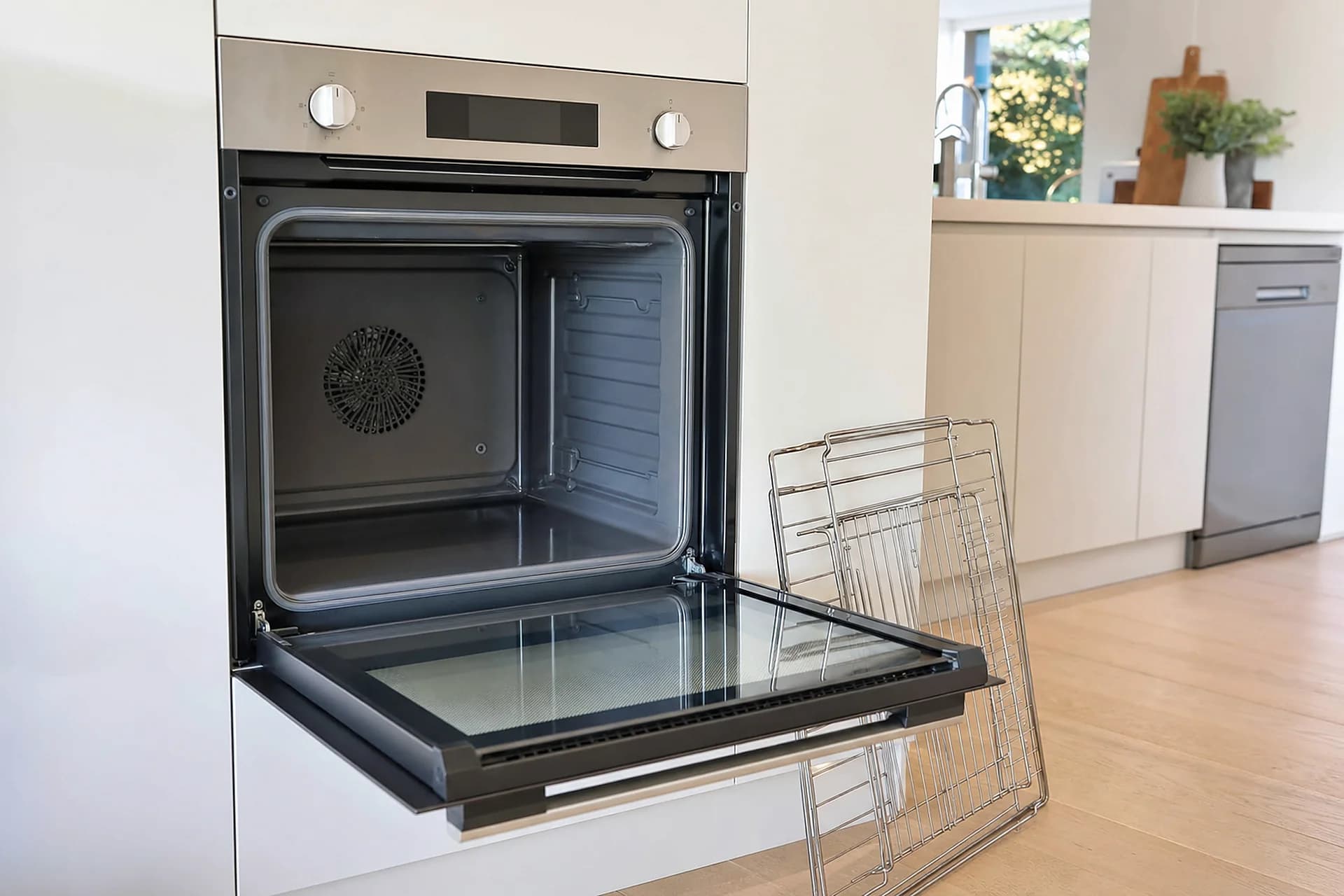 An open oven with the racks removed and standing beside it, cavity and door glass clean
