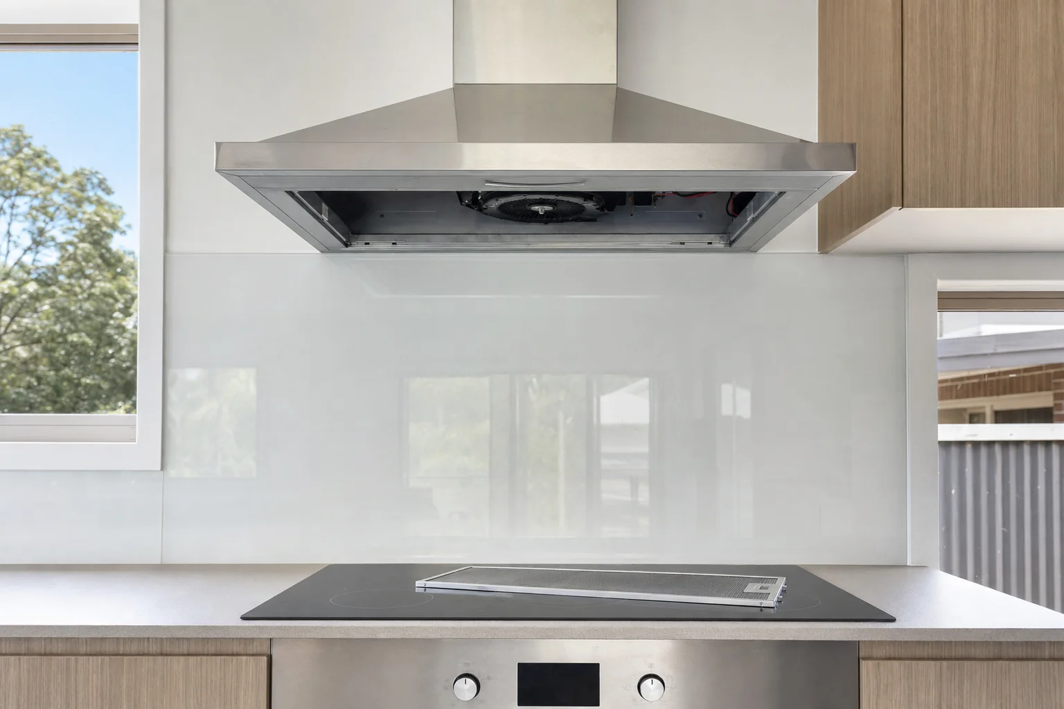 A rangehood with its metal filter removed and resting on the cooktop below