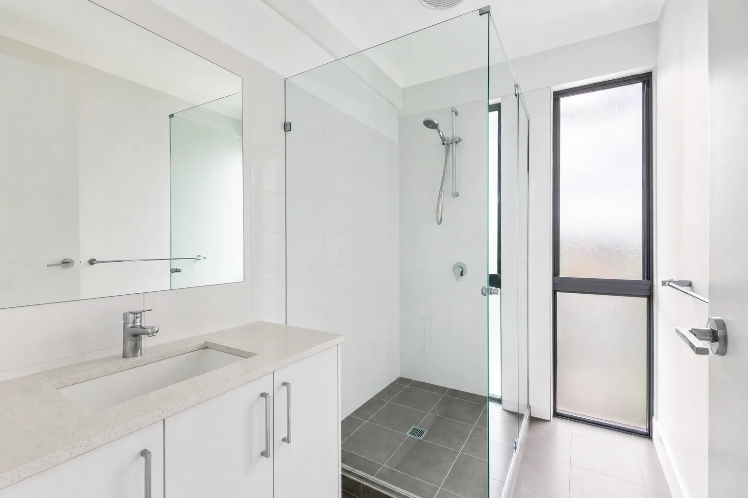 A cleaned bathroom with a clear glass shower screen