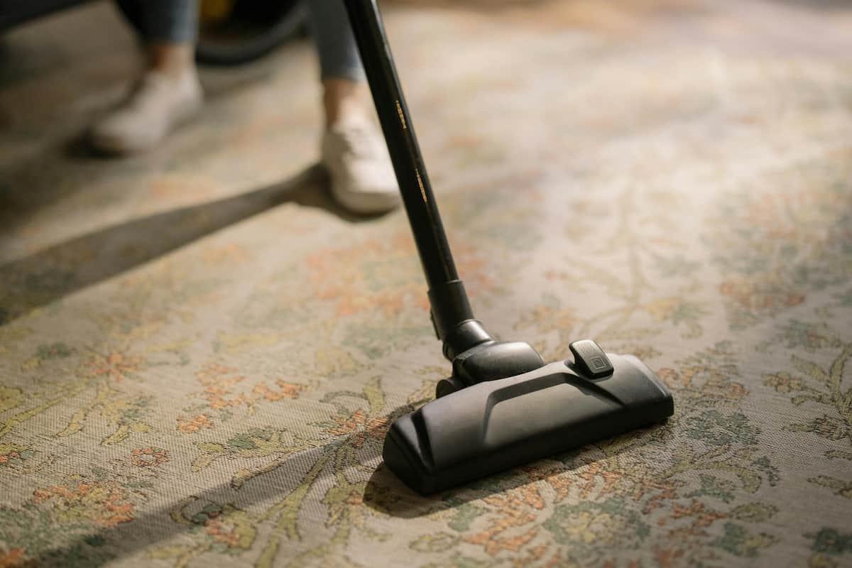 A vacuum cleaner in use on a patterned carpet, removing dust and dirt for a thorough clean.