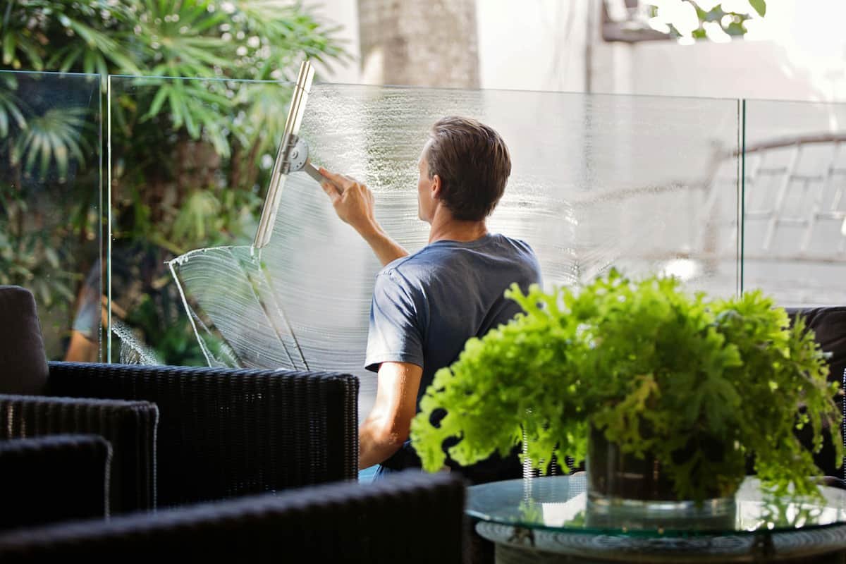 A professional cleaner using a squeegee to clean an outdoor glass panel, leaving a streak-free finish.